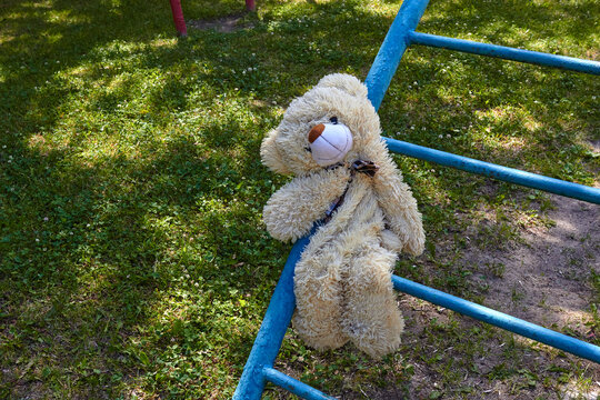 A photo of a forgotten stuffed teddy bear toy on a playground. Abandoned items. Children games.