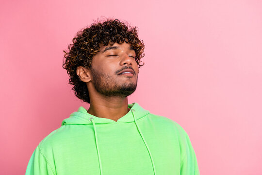 Portrait of dream young indian man wearing green hoodie closed eyes imagine his beautiful life in america isolated on pink color background