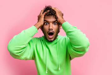 Portrait of speechless funny young indian guy green sweatshirt confused hands touch head shocked...