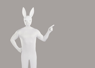 Man disguised in rabbit costume advertises something on blank grey copyspace background. Anonymous...