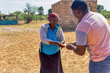 village african woman receiving money from a young man in the yard