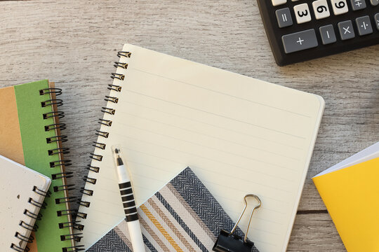 Top photo of a business workplace with pen, notepads, papers and calculator on wooden background with copy space
