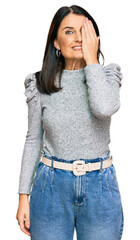 Fototapeta premium Middle age brunette woman wearing casual clothes covering one eye with hand, confident smile on face and surprise emotion.