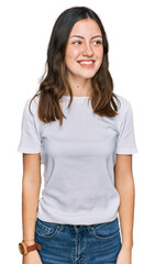 Obraz premium Young beautiful woman wearing casual white t shirt looking away to side with smile on face, natural expression. laughing confident.