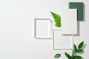 Realistic glass cylinder pedestal with a touch of green leaves on a clean white background. Minimalist scene for mockup product staging and showcase, featuring abstract vector geometric forms.
