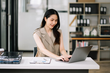 Asian Businesswoman Analyzing Finance on Tablet and Laptop at modern Office Desk tax, report,
