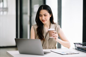 Fototapeta premium Asian Businesswoman Analyzing Finance on Tablet and Laptop at modern Office Desk tax, report,