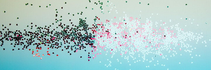 Greeting background with empty space. Pink, red sparkle sequins, glitter in heart shape on a gentle blue background. Top view, web banner
