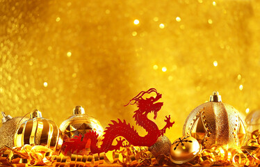 asian red dragon and festive shiny christmas decorations close up on light golden abstract...