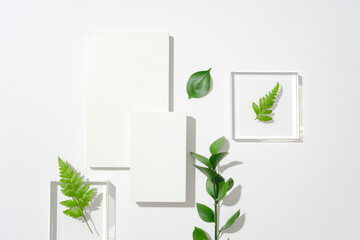 Two white podiums and two transparent glass podiums are decorated with green leaves and fern leaves...
