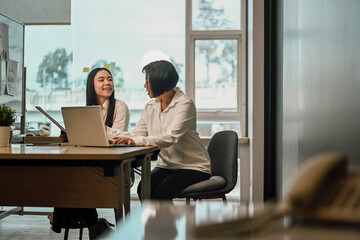 Professional mature business woman explaining work tasks to young female colleague at office