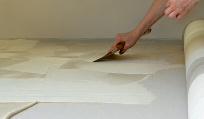 Man prepares the floor with glue for a new carpet.