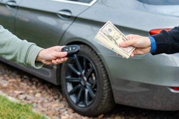 Deal of buy or rental car concept. Hand with car keys, other hand gives money.