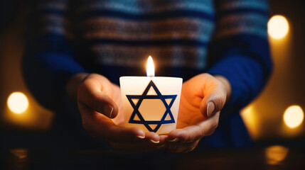 Woman holding in hands burning candle with star of David. International Holocaust Remembrance Day...