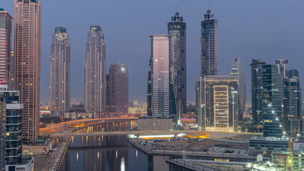 Cityscape with skyscrapers of Dubai Business Bay and water canal aerial night to day timelapse.