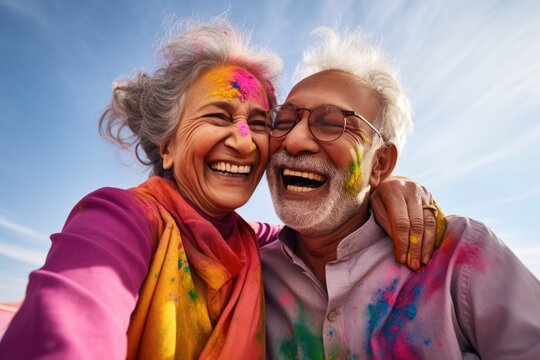 Senior couple of Indian ethnicity  celebrating Holi festival with colours in the outdoor
