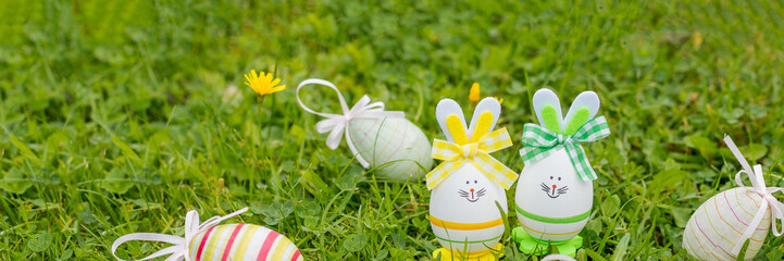 Easter object. colored hand painted easter eggs with bunny ears, symbols of the holiday. composition on green grass background. web banner. copy space