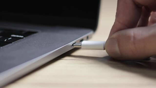 Man is insert the cable USB Type C into the Port for fast charging laptop. Close up, modern technology photo.