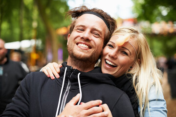 Happy couple, portrait and hug at festival for love, care or support at outdoor party, DJ event or music. Man and woman smile in embrace, affection or trust for festive celebration or summer break - obrazy, fototapety, plakaty