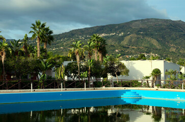 Scenic landscape view of large swimming pool and palm trees in the background. Marina di Patti is a town and comune in northeastern Sicily, southern Italy. Travel and tourism concept