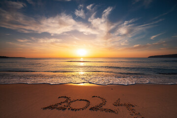 Happy New Year 2024 concept, lettering on the beach. Written text on the sea beach at sunrise.