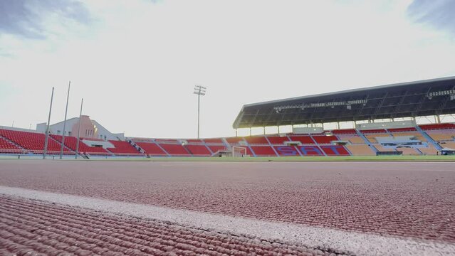 Asian para-athletes with prosthetic blades sprint on a running track at stadium.