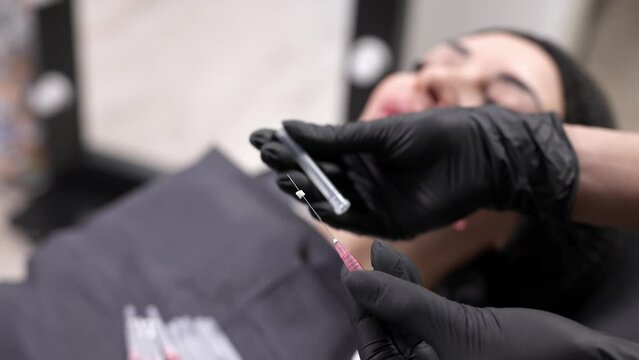 Preparing needles for face thread lifting in a modern clinic. Close-up of a face threadlift needle on an adult client. Facelift concept, surgery, skin rejuvenation.