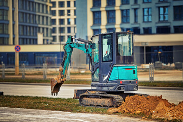 Compact crawler excavator on construction site, dig trench in modern residential district. Mini...