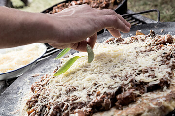 Pasta a la parrilla con salsa y queso rayado, con una mano decorando con hojas verdes