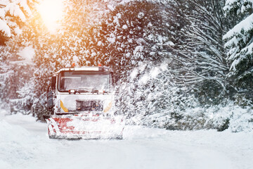 A snowplow truck clears the highway from snow during a winter storm. Snow blowing out of the plow...