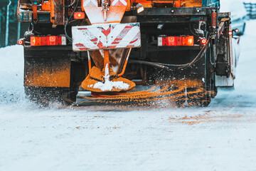 A snowplow truck applies salt and sand as the truck works to clean the snowy road. Roads and...