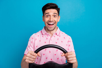 Photo of astonished crazy cheerful person open mouth arms hold steering wheel isolated on blue...