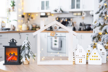 Key and tiny house of a small size on cozy home with Christmas decor on table of festive white...