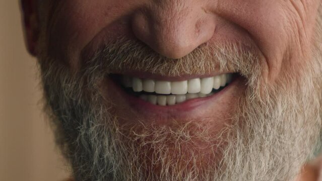 Close up male white healthy teeth smiling cropped view happy satisfied smile cheerful positive unrecognizable old senior mature man with gray hair beard bearded grandfather dental prostheses medicine