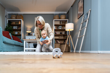 Grandmother taking care of her grandchild while his parents working. Senior woman work as a nanny,...