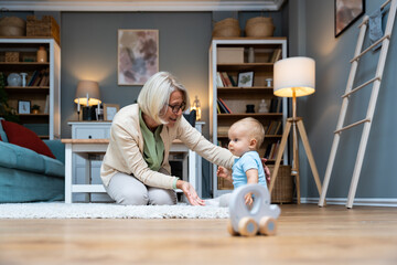 Grandmother taking care of her grandchild while his parents working. Senior woman work as a nanny,...