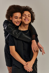 jolly stylish african american brother and sister in trendy outfits hugging and smiling happily