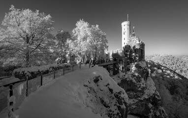 Fairytale castle “Lichtenstein“ with frosted trees near Honau Reutlingen on a cold sunny december morning. Winter wonderland in Baden-Württemberg, southern Germany. Nostalgic black and white greyscale