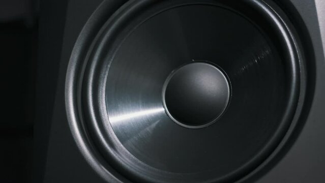 Studio bass speaker vibrates from loud music in a recording studio, close-up. Modern loudspeaker membrane pumping from bass sound in slow motion. Working bass cone on low frequency. Hi-fi sound system