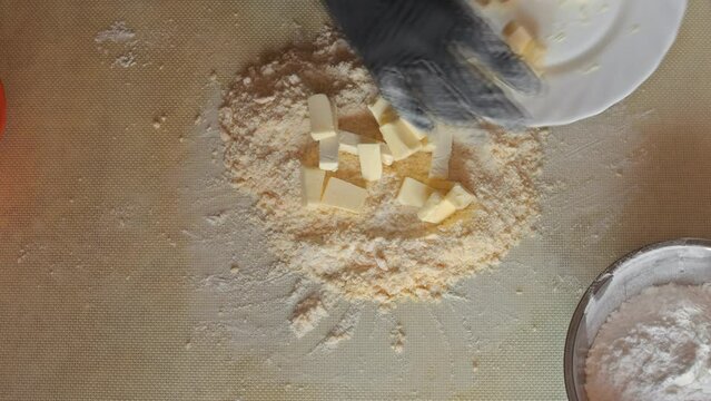 Adding butter to a mixture of flour and egg to make shortbread. The process of making shortbread on a silicone mat