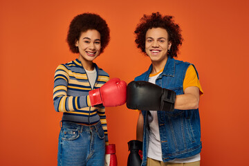 jolly african american siblings in boxing gloves having fun together on orange backdrop, family