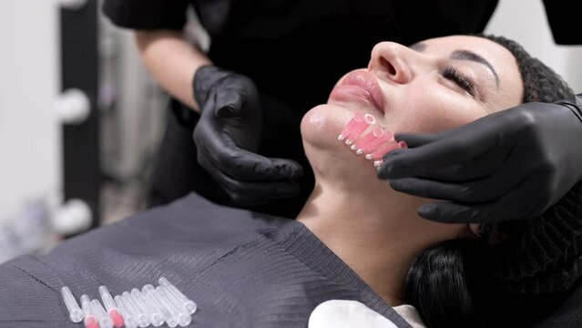 An adult woman undergoes a thread lifting procedure in a cosmetology clinic. Anti-aging facial rejuvenation. A cosmetologist implants cosmetic threads under the skin to eliminate facial ptosis.