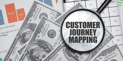 CUSTOMER JOURNEY MAPPING word on magnifying glass with dollars and charts