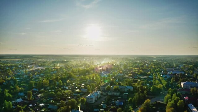 A small low-rise town with green streets and stove-heated houses, sunlit in clear weather. Aerial Drone Shot