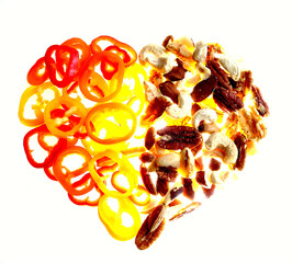 Heart shape made from Orange, Yellow and red chillies. Brazil, pecan nuts, walnuts and cashews, on a light table with intentionally strong lighting to overexpose centre. Heart healthy foods concept.