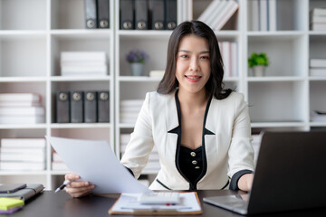 Obraz na płótnie Canvas Young Asian business woman sitting working in modern office. Asia business woman sitting smiling and happy with laptop computer in the office.