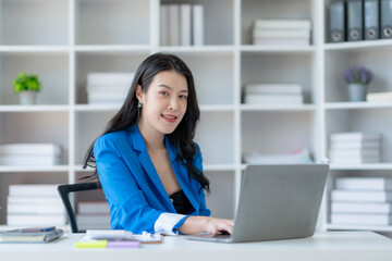 Young Asian business woman sitting working in modern office. Asia business woman sitting smiling...