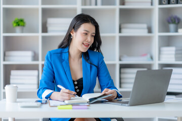 Young Asian business woman sitting working in modern office. Asia business woman sitting smiling and happy with laptop computer in the office.