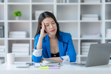 Fototapeta premium Stressed Asian Businesswoman Coping with Corporate Pressure at Office Desk. Workplace Burnout Concept.