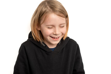 A young boy of ten, sporting long hair, showcases a bright and cheerful smile against the simplicity of a white background